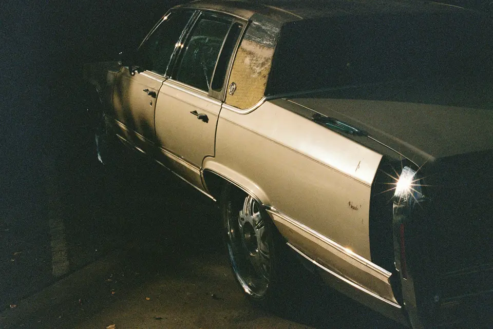 A cream-colored cadillac parked at night — Austin