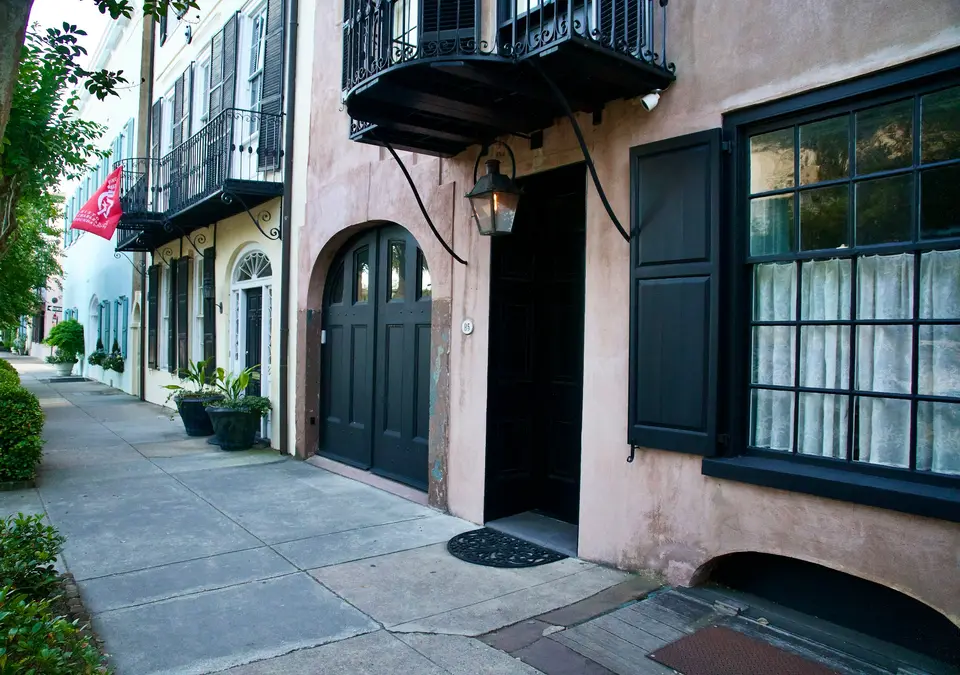 a building with black shutters and a black door — Charleston
