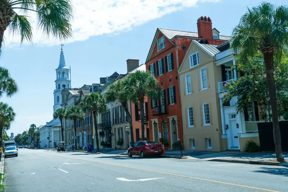 red car parked beside brown concrete building during daytime — Charleston