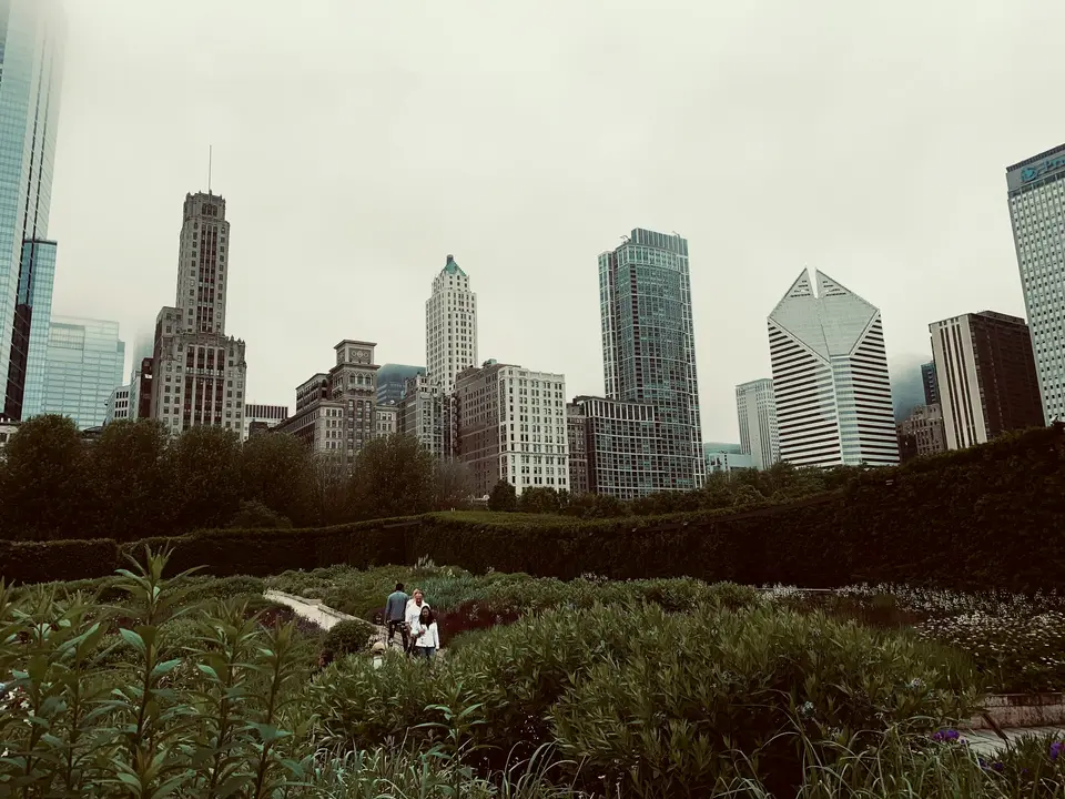 man in white shirt sitting on green grass field near high rise buildings during daytime — Chicago