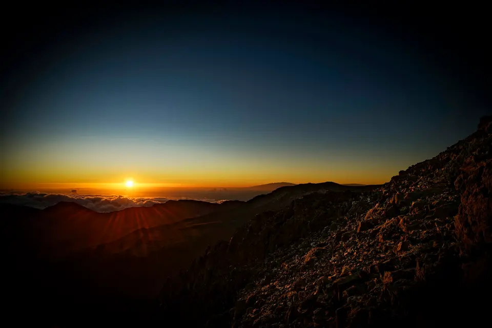 Sunrise over a mountain range with clouds — Maui