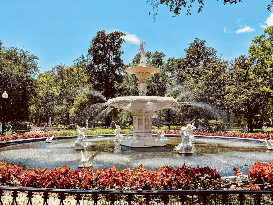 red flowers near white outdoor fountain during daytime — Savannah