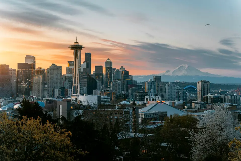 The Space Needle and Seattle skyline with Mount Rainier under a warm orange sky — Seattle