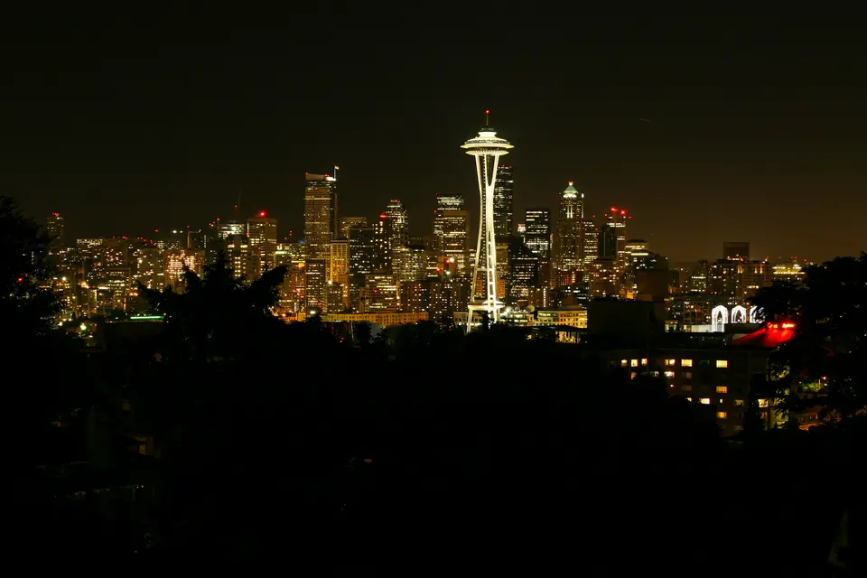 a view of a city at night with the space needle in the background — Seattle