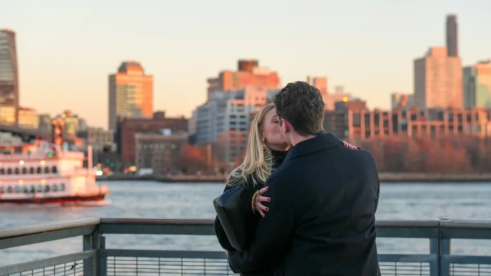 Couple kissing with city skyline at sunset
