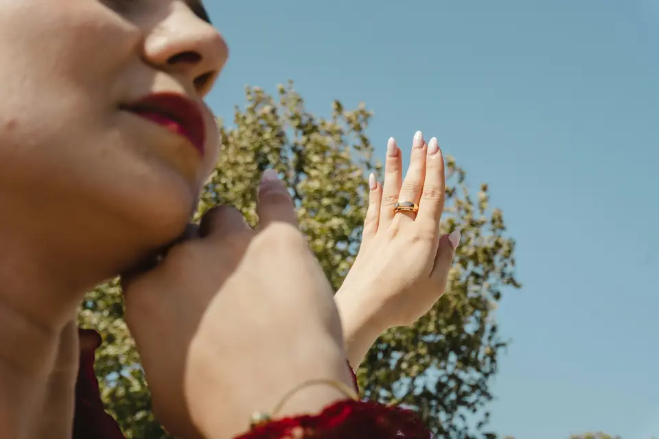 Woman's hands displaying a ring under a clear sky