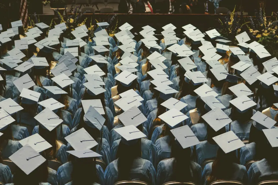 A large group of graduates in light blue gowns and caps at a ceremony