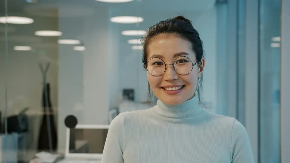 A smiling woman with glasses in an office