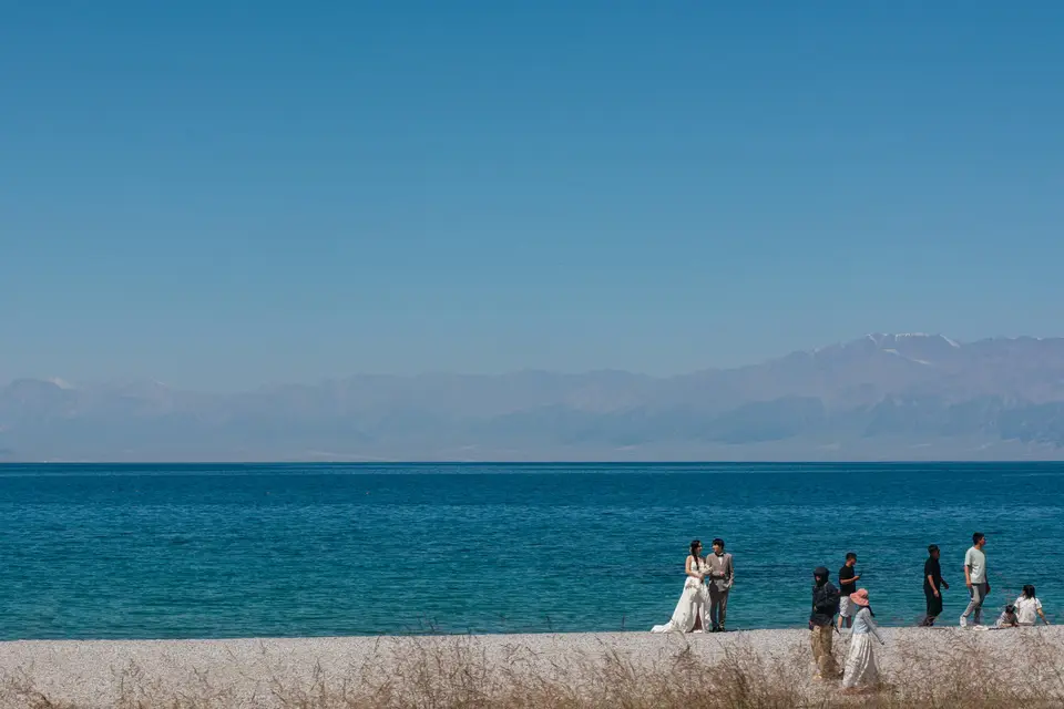 People gathered on a wall by the blue ocean